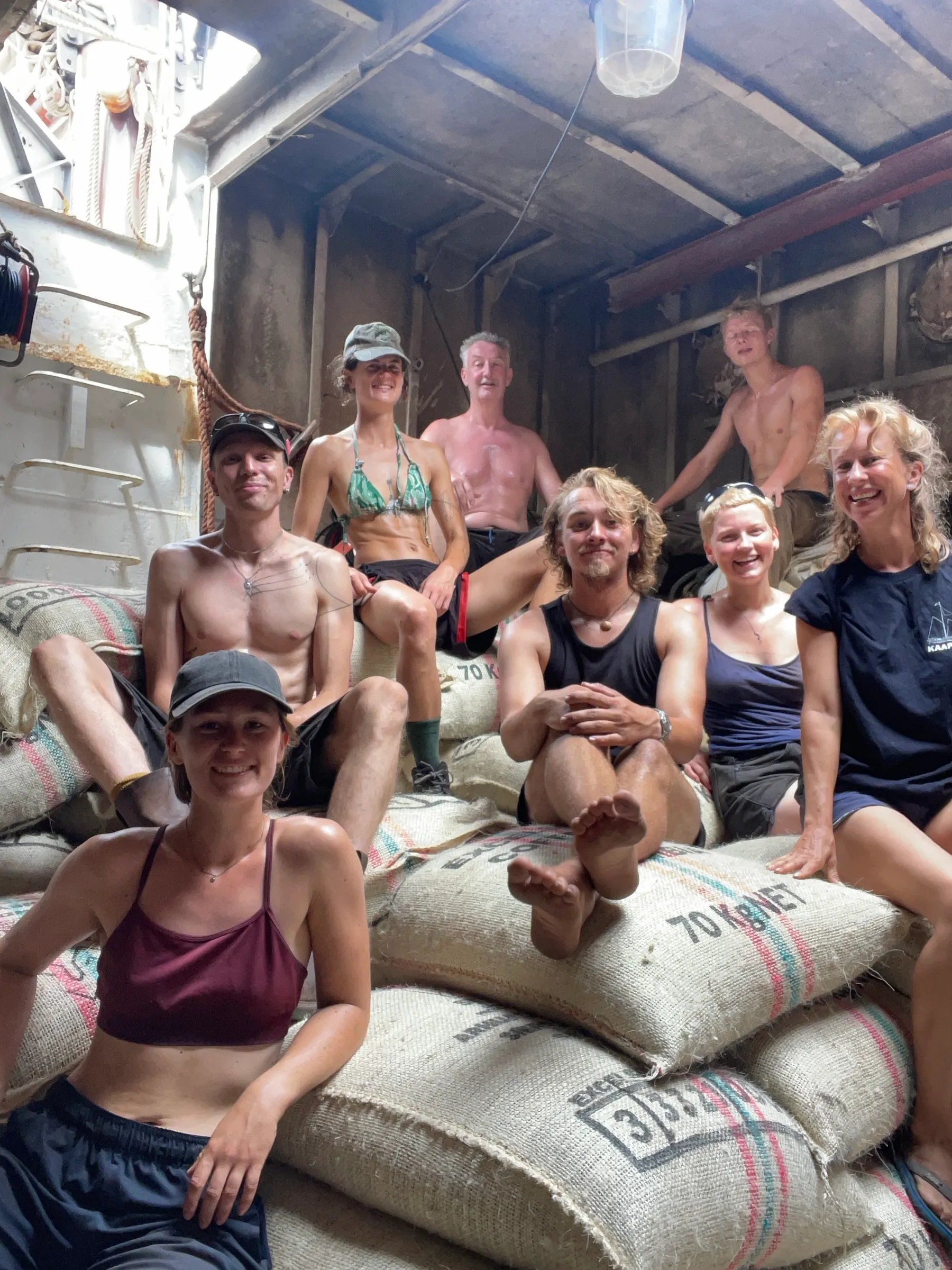 The crew sitting on coffee sacks below deck, smiling